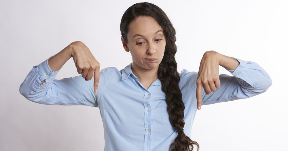 woman with brown hair and light blue shirt pointing downwards with both hands. pda and the low demand approach